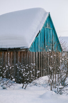 A large layer of snow on the roof of the barn