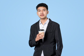 Young handsome asian businessman smiling while holding hot coffee in takeaway paper cup isolated on blue light background. Business Person concept.