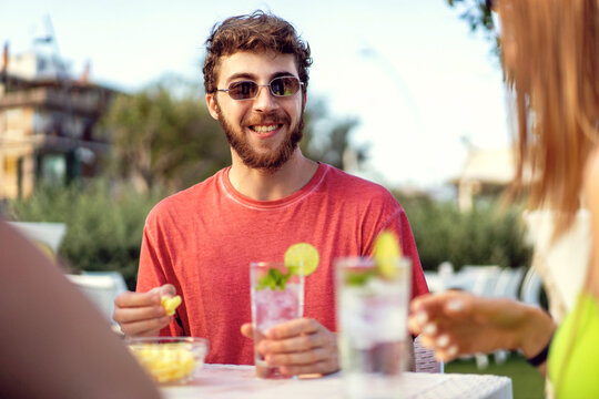 Young Man Enjoying a fresh cocktail and Appetizer at an Outdoor Pub