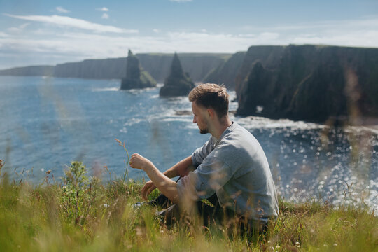 Man relaxing at Sea Stacks At Duncansby Head. Highlands, Scotland