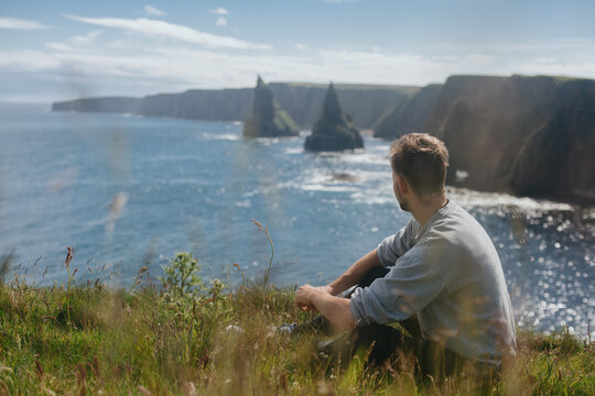 Man relaxing at Sea Stacks At Duncansby Head. Highlands, Scotland