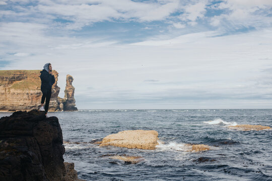 Woman relaxing on the cliff on the ocean beach - Powered by Adobe