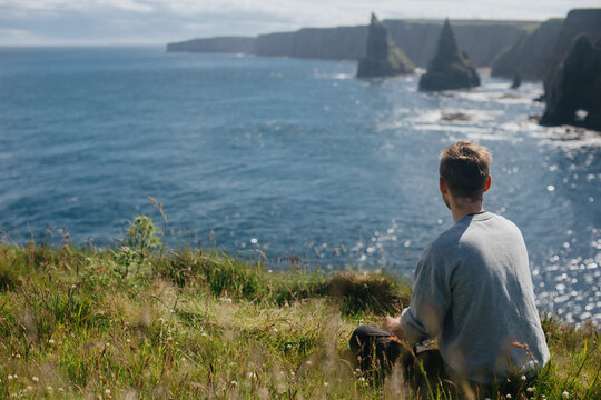 Man relaxing at Sea Stacks At Duncansby Head. Highlands, Scotland