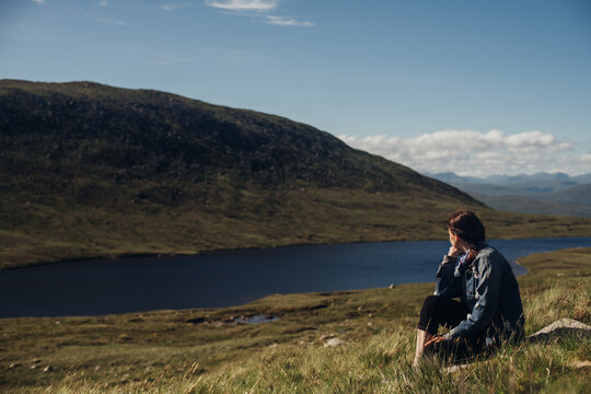 Woman relaxing at mountain lake. Highlands, Scotland