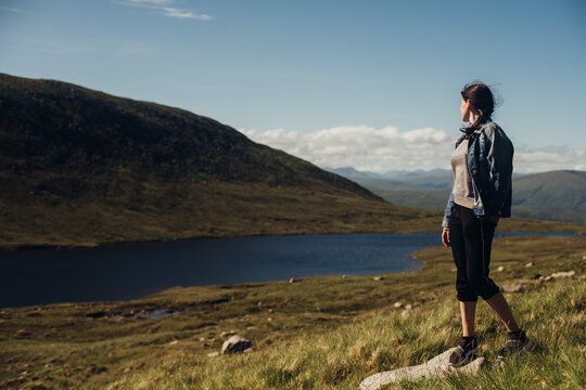 Woman relaxing at mountain lake. Highlands, Scotland