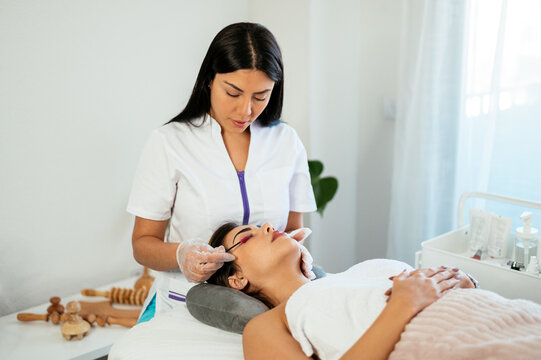 beautician brushing eyelashes of female client