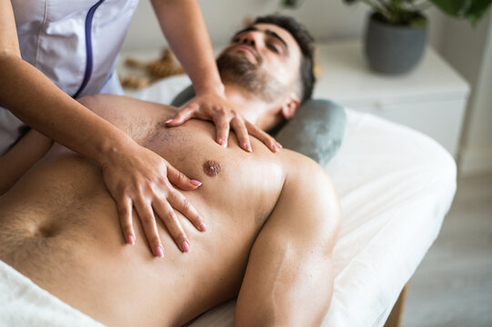 Crop masseuse massaging chest of client