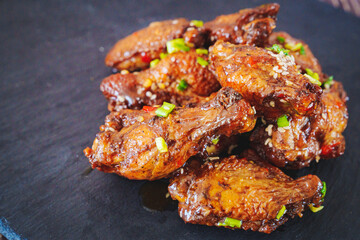 fried chicken with garlic and sesame in caramel on a black tray.