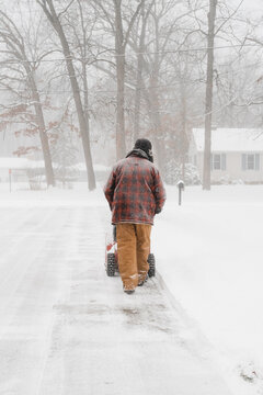 Anonymous male clearing snow from driveway with machine