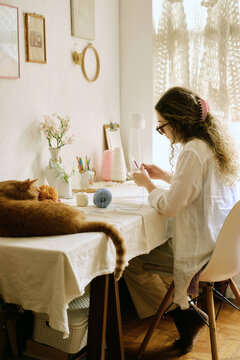 Young artist crocheting with her cat