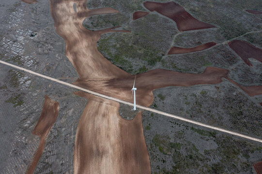 road crosses frame with wind generator and fields of agriculture. 