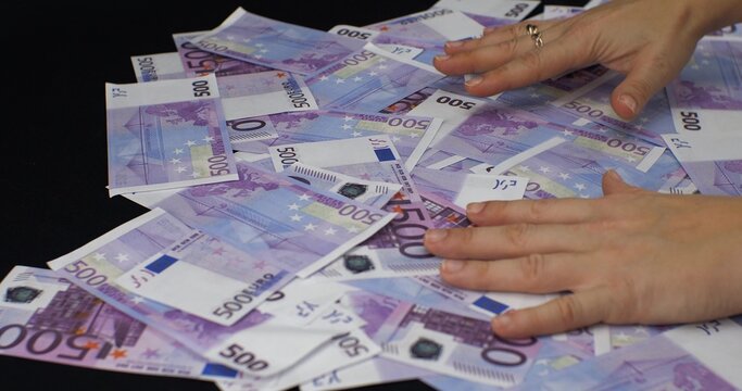 Hands Raking A Big Pile Of Money Er Bills From A Black Background. Women's Hands Lie On Top Of A Large Pile Of Five Hundred Euro Bills. The Concept Of A Big Win Euro Bills.