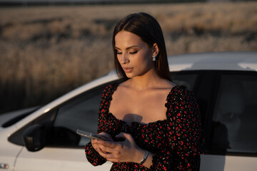 portrait of attractive beautiful woman with mobile phone near car