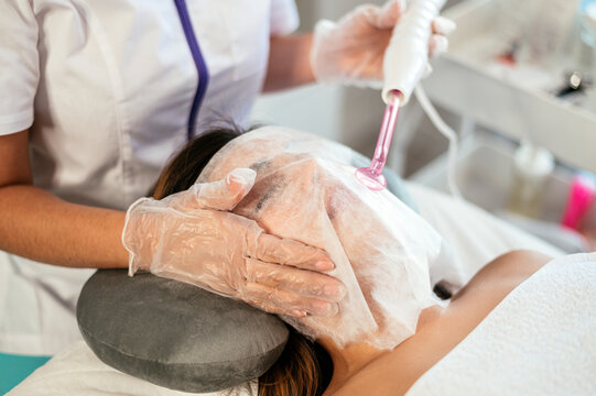 Beautician performing darsonvalization in salon