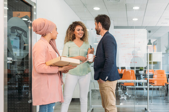 Smiling multiracial coworkers talking during coffee break in office