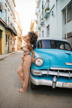 Cuban woman touching hair near vintage car