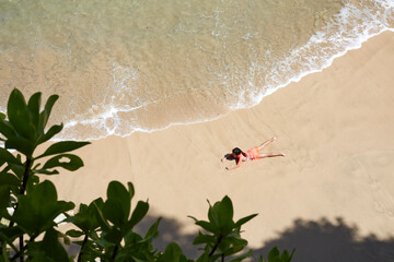 Asian little girl lying on the beach, beautiful clear sea water