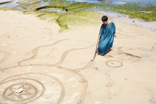 Asian female artist draws mandala painting on the beach by the sea