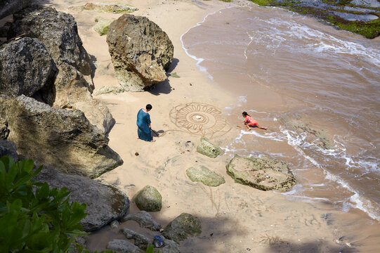 Asian female artist and her daughter draw mandala painting on beach