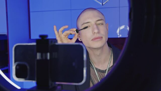 closeup view of a bald gay man making eyelashes in a live video, makeup tutorial LGBT concept. High quality 4k footage