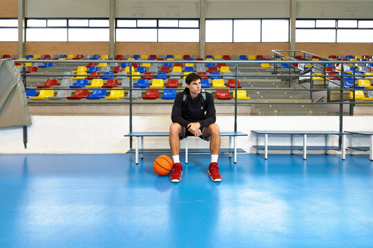 Sportsman sitting near ball