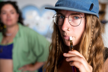 Young beautiful woman taking a drag from vape pen