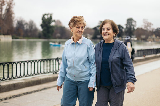 Elderly women in sportswear walking in a park by a lake