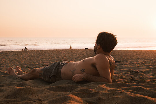 man lying on the sand in the sunset