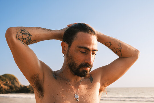 man with hairy armpits on the beach dries the water after a swim 