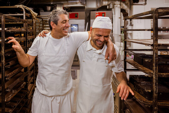 Happy cooks hugging near trolleys