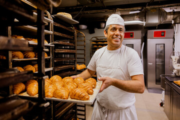 Male baker checking croissant on tray