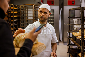 Baker giving bread to courier with smartphone
