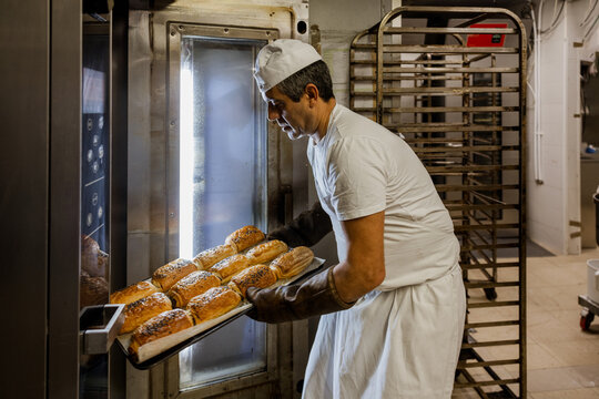 Man taking buns out of oven
