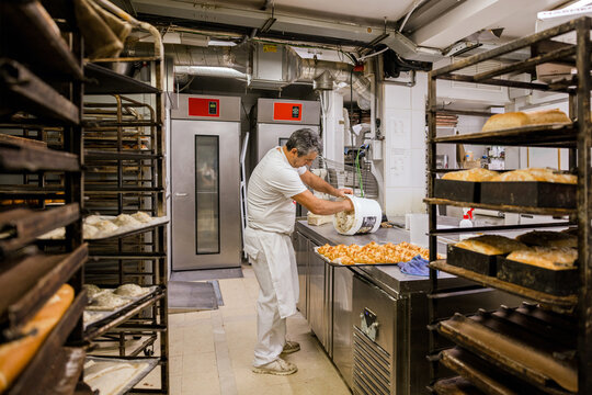 Male baker removing ingredients from bucket