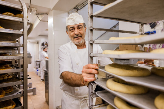 Middle aged baker pushing trolley with pastry