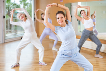 Active middle-aged woman practicing aerobic dance in training hall during fitness dance classes....