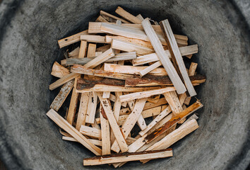 Chopped, sawn boards, firewood lie in a metal tank. Close-up photo, texture, top view.