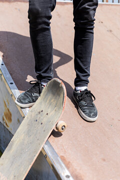 Male legs standing on a ramp with a skateboard aside at a skate park