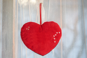 Red heart hangs on white curtain