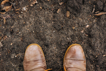 The worker is standing in two brown leather boots with long laces against the background of the...