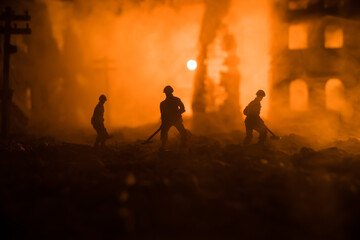 Fototapeta premium War Concept. Military silhouettes fighting scene on war fog sky background. Sappers clears mines at the site of recent fighting zone. Battle in ruined city.