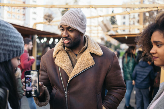 Young man taking a photo at a winter market in the city