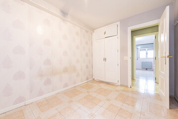 old room with papered walls and built-in wardrobe with white doors and two-tone tiles