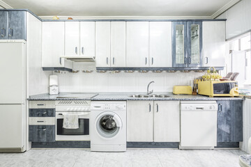 Front view of an old-fashioned conventional kitchen with white cabinets and appliances and some...