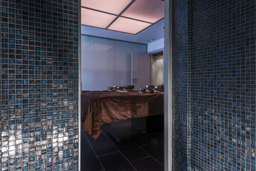 A blue glass tiled sauna in a massage parlor with Tibetan bowls on a table