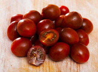 Ripe red cultivated species kumato tomatoes on wooden background. Healthy vitamin product