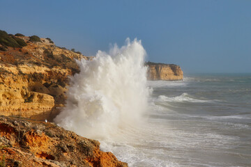 Large waving splashing against cliffs on a windy winter day in Carvoeiro, Portugal.