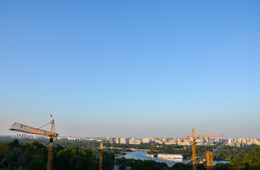 Obraz premium Tower crane on the background of Dnipro river and left bank of Kyiv city. New buildings architecture and industry construction