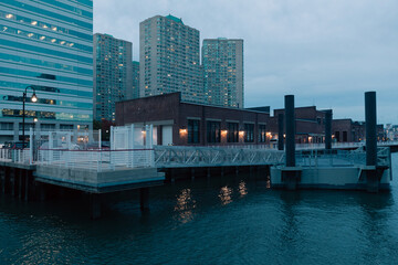 port and pier on Hudson river near modern buildings in New York City.