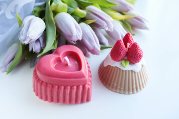 valentine's day background. candle in the shape of a heart made of natural soy wax in the shape of a heart and a bouquet of flowers